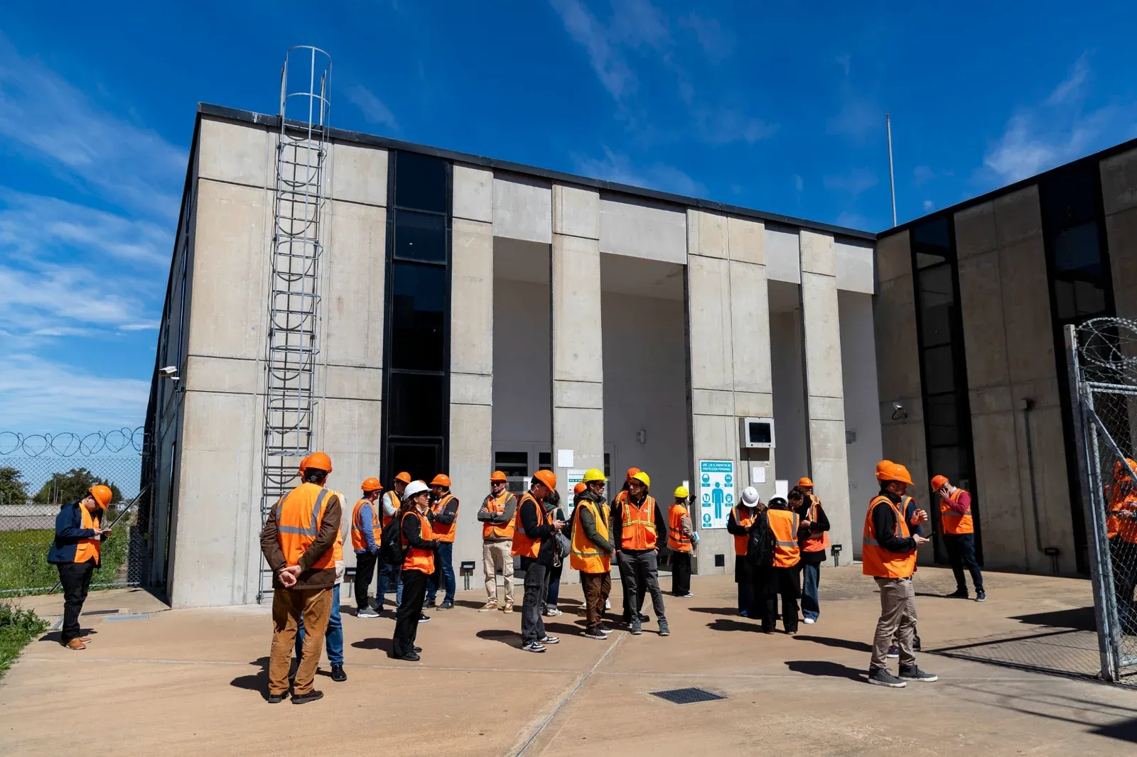 Grupo con chalecos de seguridad recorriendo una planta industrial portuaria