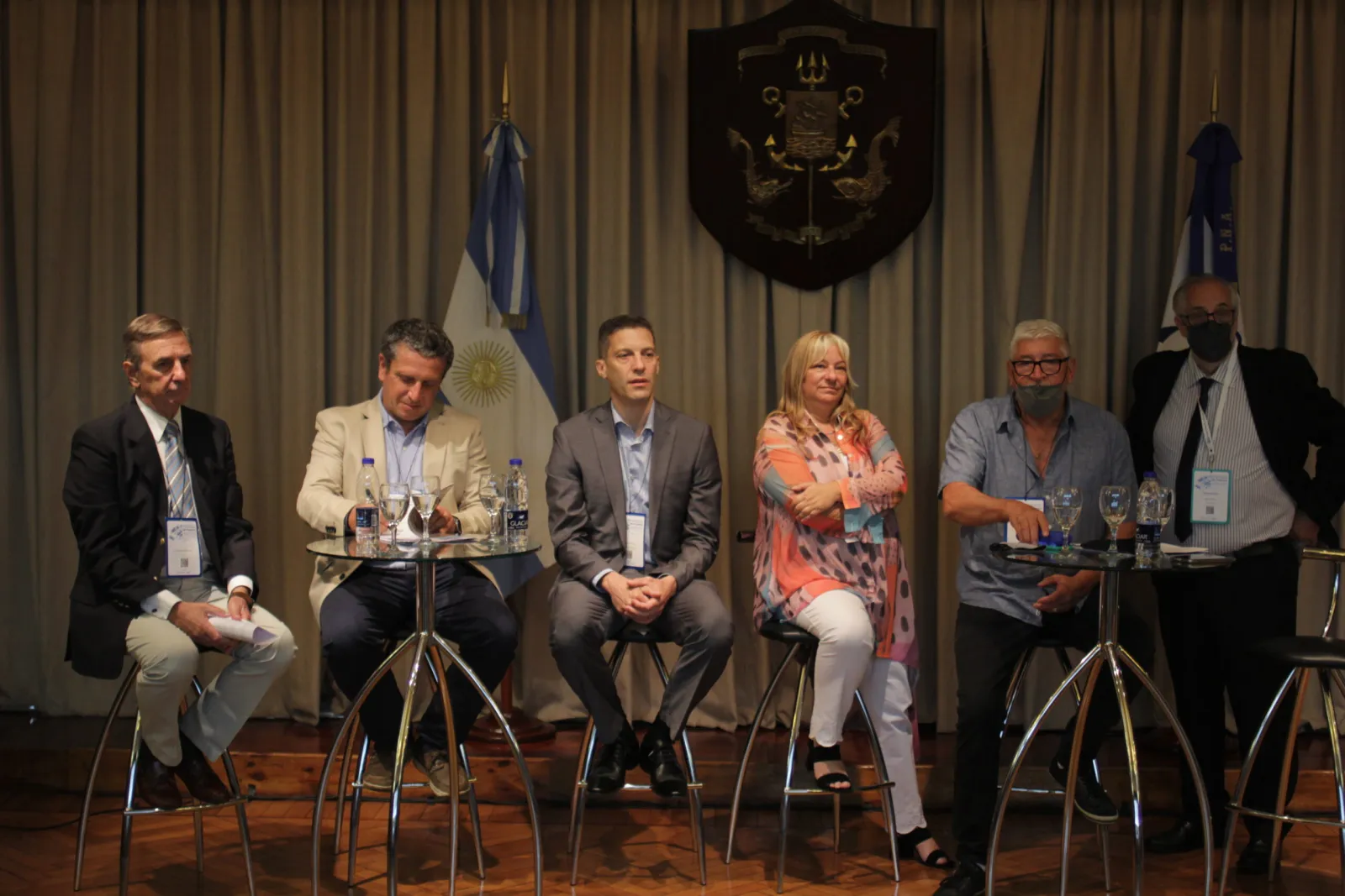 Panel de cinco expositores sentados en el escenario durante una mesa de debate